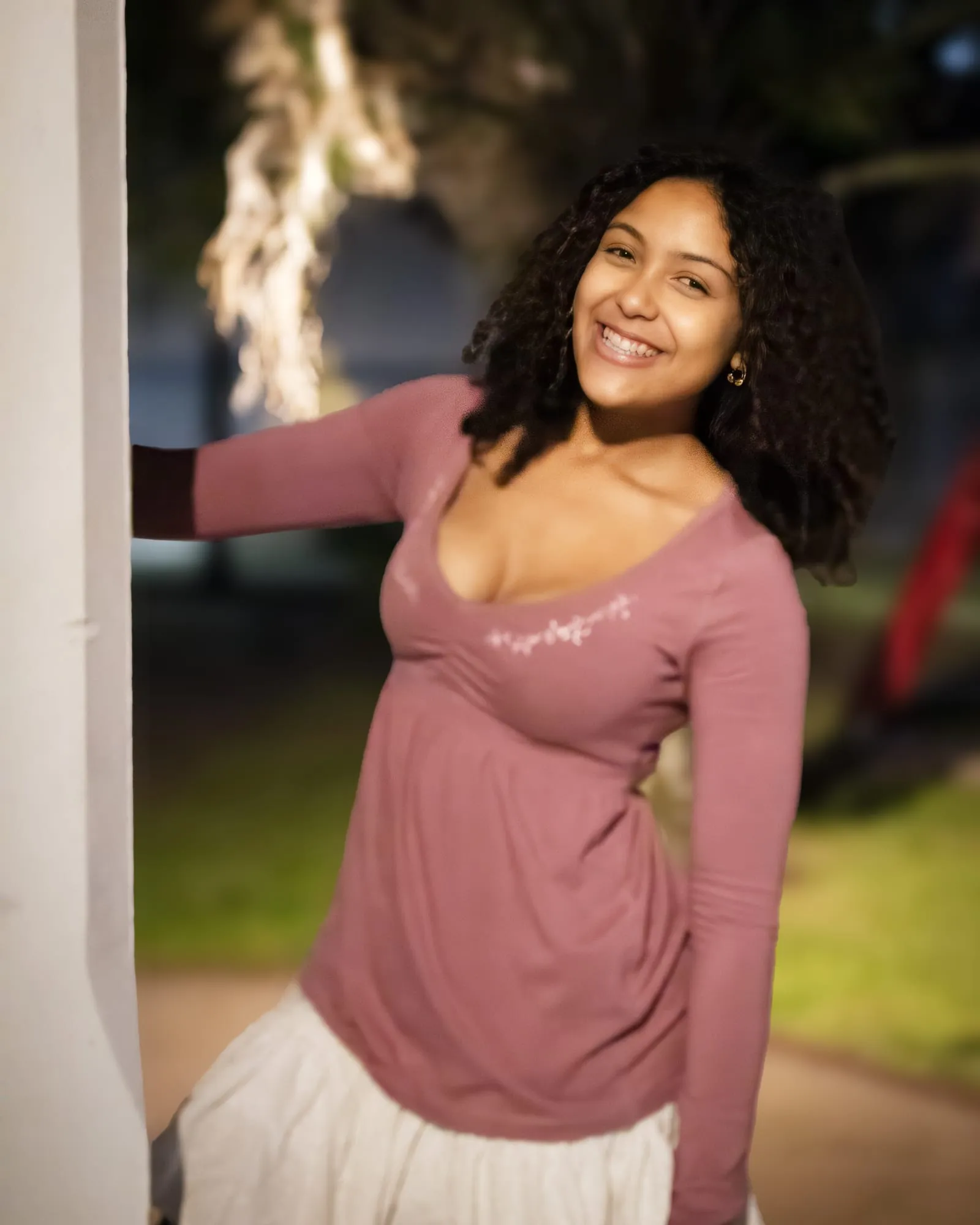 A senior smiling warmly against a white column in soft evening light