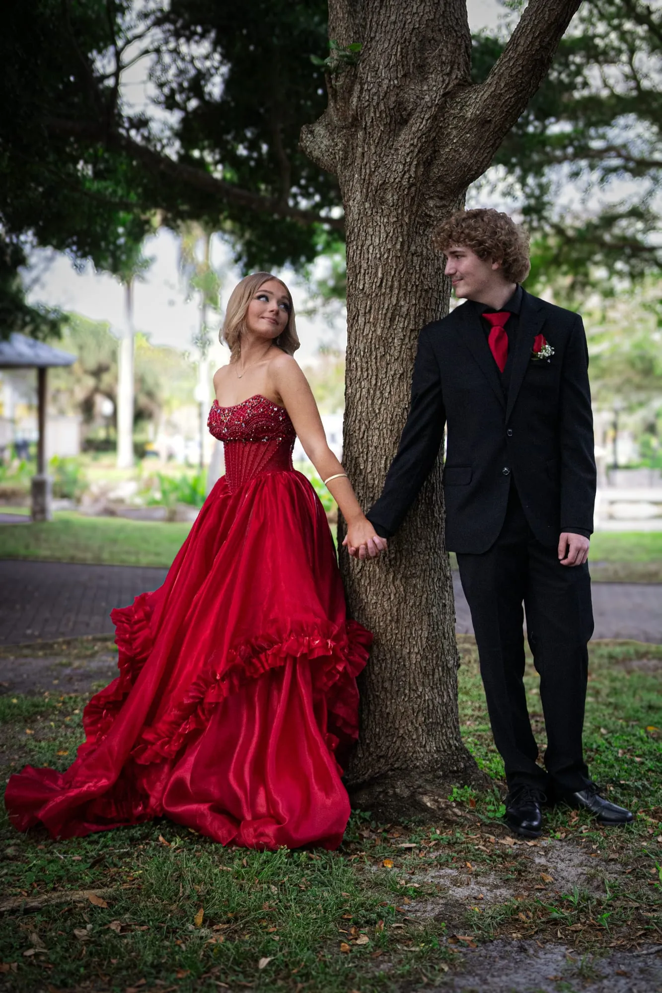 Senior portrait of a girl in a red sequined gown glancing over her shoulder in warm golden-hour light